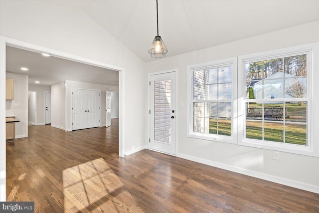unfurnished dining area with baseboards, vaulted ceiling, and dark wood-style floors