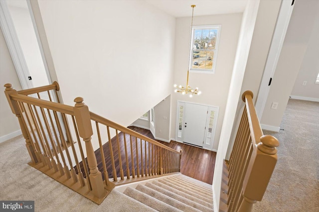 stairway with a chandelier, baseboards, and carpet floors