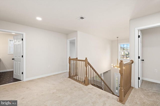 interior space with visible vents, baseboards, an upstairs landing, and carpet floors