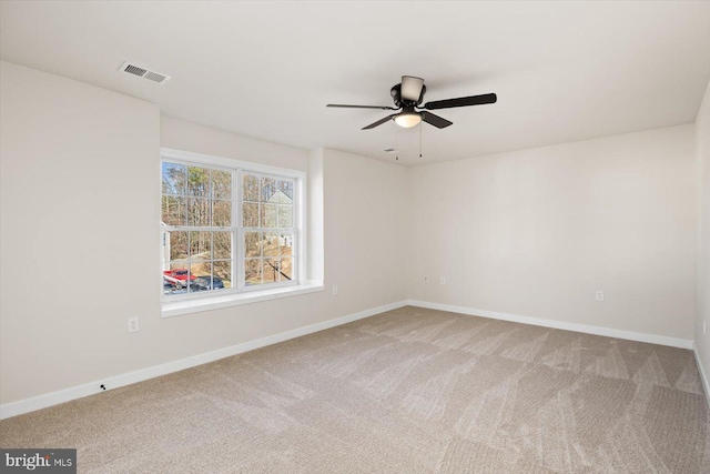 carpeted empty room with visible vents, baseboards, and a ceiling fan