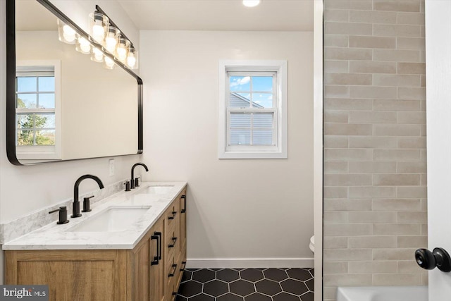 full bath with a healthy amount of sunlight, a sink, and baseboards
