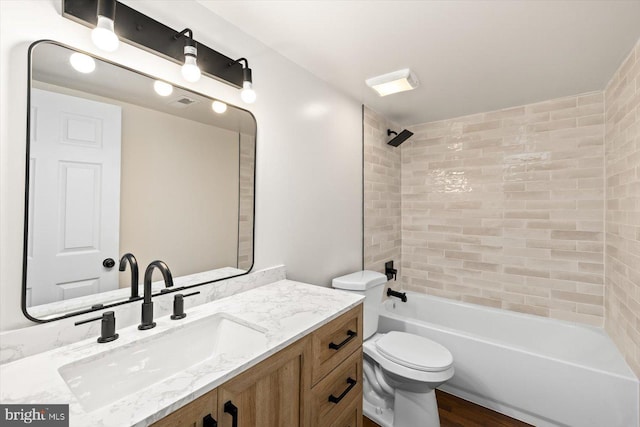 full bath with toilet, wood finished floors, vanity, and shower / tub combination