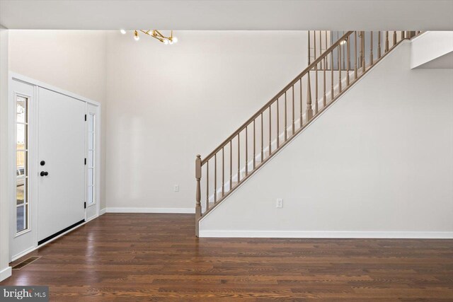 foyer entrance featuring a towering ceiling, visible vents, wood finished floors, stairs, and baseboards
