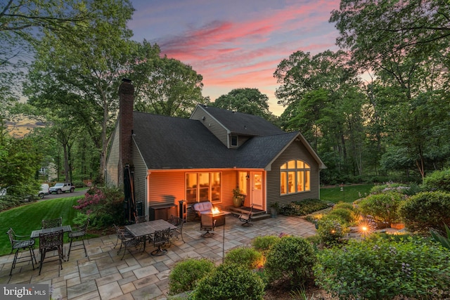 116 Amesbury Ct, Severna Park, MD 21146 - back of property at dusk featuring a fire pit, a patio area, outdoor dining space, and a shingled roof