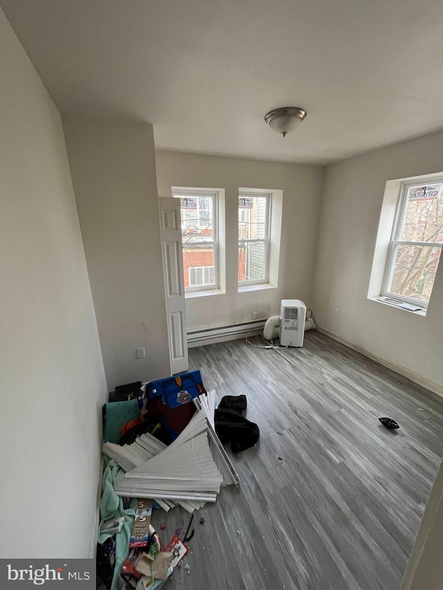 empty room with wood finished floors and baseboard heating