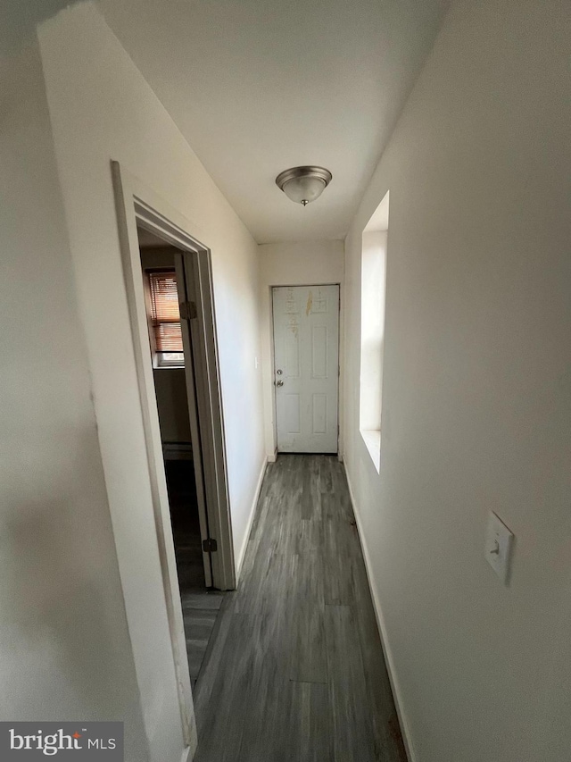 hall with dark wood-style flooring and baseboards
