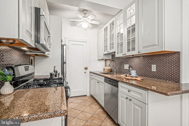 kitchen featuring light tile patterned flooring, a sink, decorative backsplash, white cabinets, and appliances with stainless steel finishes