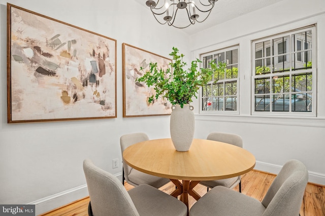 dining space with wood finished floors, baseboards, and a notable chandelier