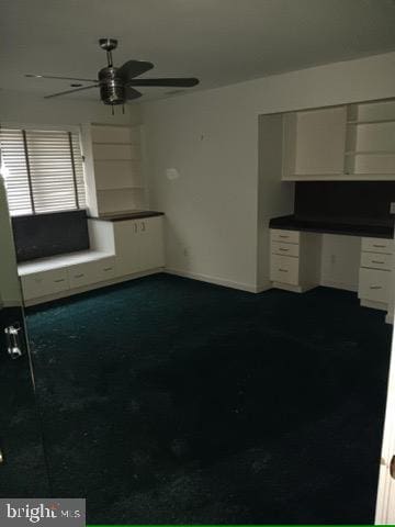 unfurnished living room with ceiling fan, dark colored carpet, and baseboards