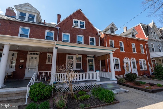townhome / multi-family property with brick siding and covered porch