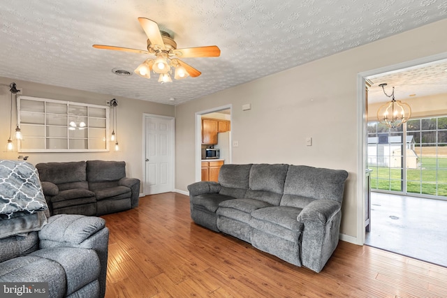 10257 Back Creek Valley Rd, Hedgesville, WV 25427 - living area with ceiling fan with notable chandelier, wood finished floors, visible vents, and a textured ceiling