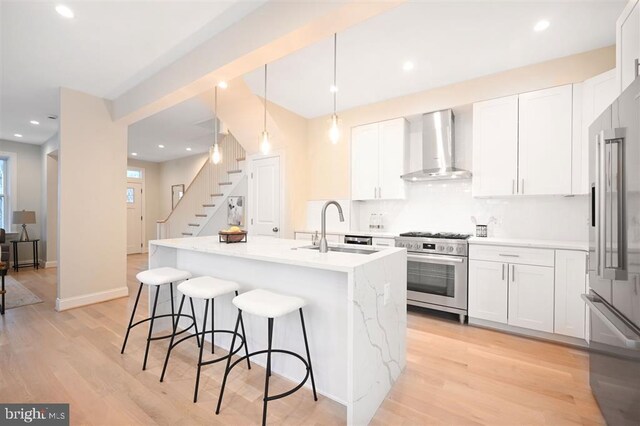 512 Peabody St NW, Washington, DC 20011 - kitchen with a breakfast bar, high quality appliances, light wood-style flooring, wall chimney exhaust hood, and a sink