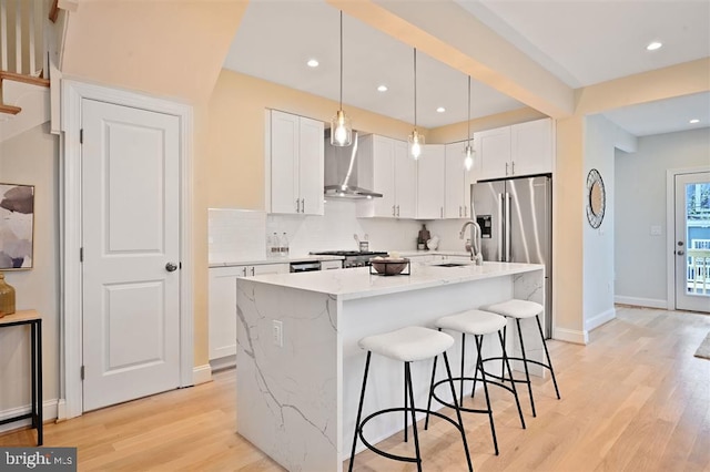 512 Peabody St NW, Washington, DC 20011 - kitchen featuring stainless steel fridge, a sink, wall chimney range hood, a kitchen bar, and light wood-style flooring