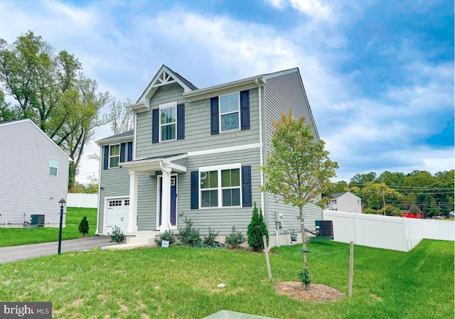 traditional home with a front lawn, driveway, central AC, fence, and a garage