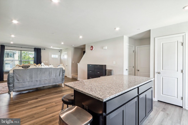 kitchen with recessed lighting, open floor plan, wood finished floors, and a kitchen island
