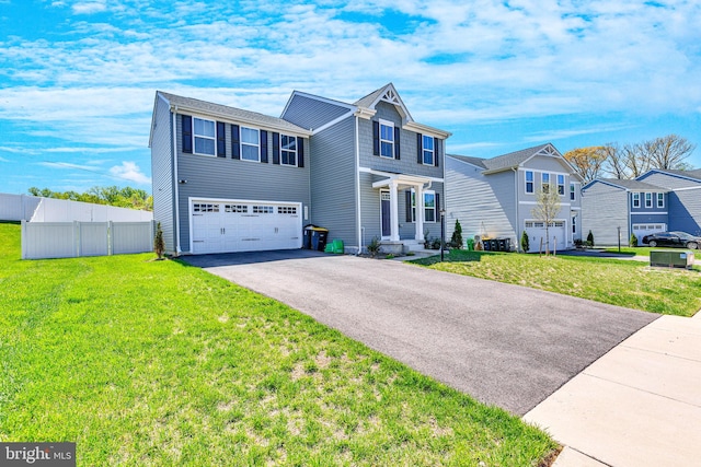 traditional-style home with fence, a front yard, driveway, and a garage