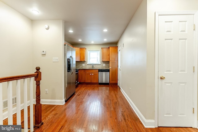 kitchen featuring dark countertops, stainless steel appliances, wood-type flooring, backsplash, and baseboards