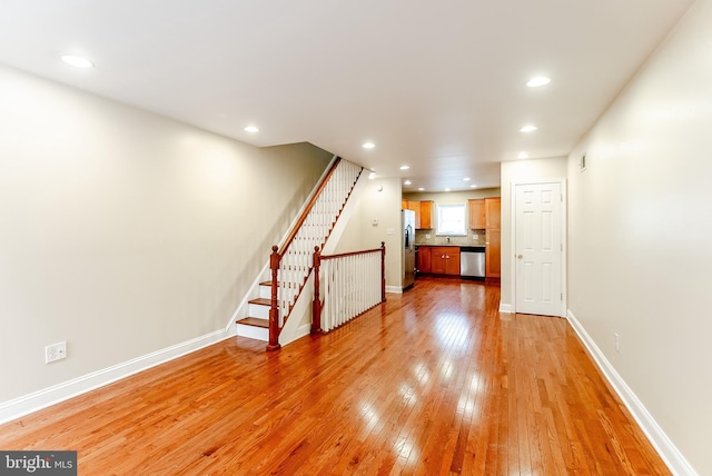 unfurnished living room featuring stairway, baseboards, light wood finished floors, and recessed lighting