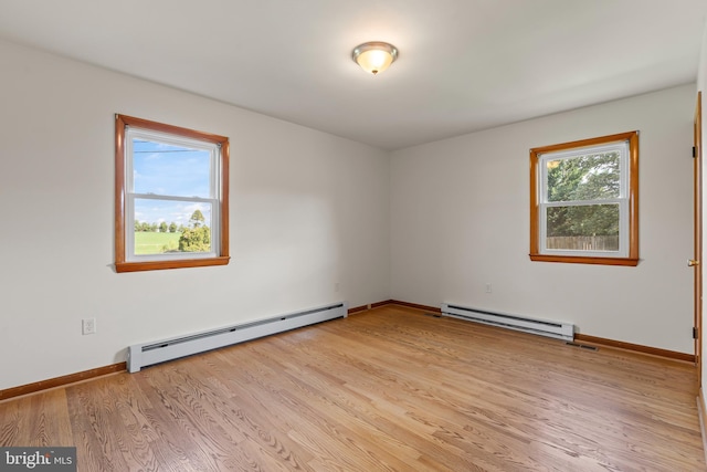 spare room with light wood finished floors, a baseboard radiator, and baseboards
