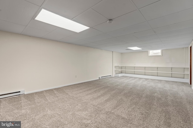 basement with a paneled ceiling, a baseboard radiator, carpet flooring, and baseboards