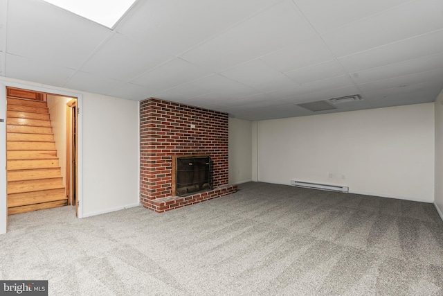 unfurnished living room with visible vents, a brick fireplace, carpet, stairs, and a baseboard heating unit