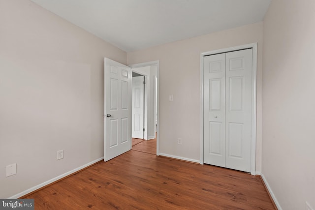 unfurnished bedroom featuring a closet, wood finished floors, and baseboards