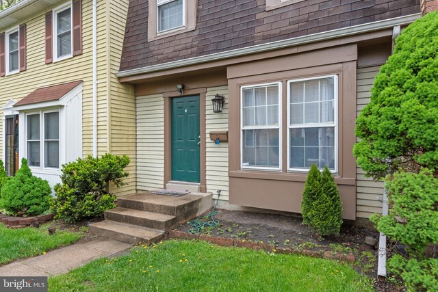 doorway to property with a shingled roof and mansard roof