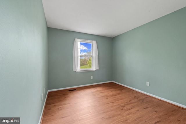 spare room with visible vents, wood finished floors, and baseboards