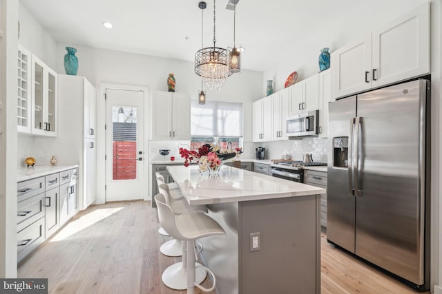 2237 N Hope St, Philadelphia, PA 19133 - kitchen featuring white cabinets, stainless steel appliances, a kitchen island, decorative backsplash, and a notable chandelier