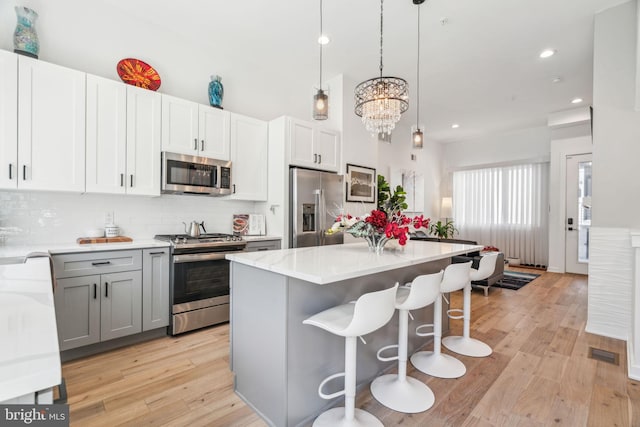 2237 N Hope St, Philadelphia, PA 19133 - kitchen with a center island, decorative backsplash, light wood-style flooring, appliances with stainless steel finishes, and visible vents