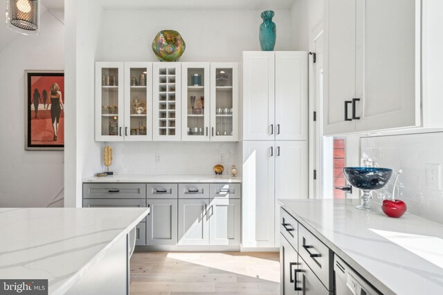 2237 N Hope St, Philadelphia, PA 19133 - kitchen featuring light stone counters, glass insert cabinets, decorative backsplash, light wood-style flooring, and white cabinetry
