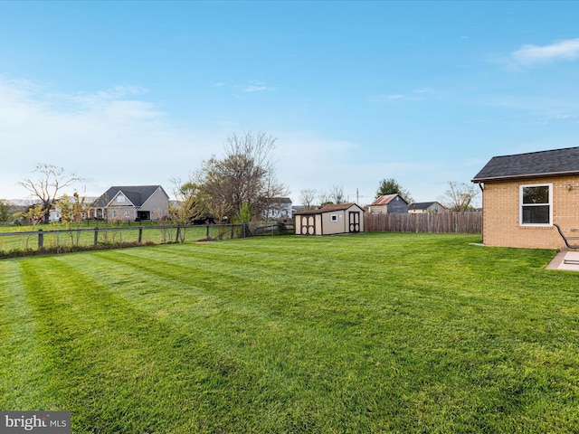 view of yard with a fenced backyard, an outdoor structure, and a storage unit