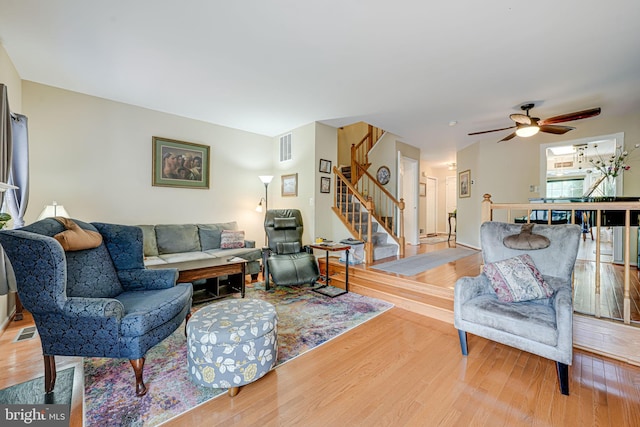 living room with wood finished floors, stairs, and ceiling fan
