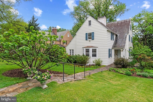 back of house with a chimney and a lawn