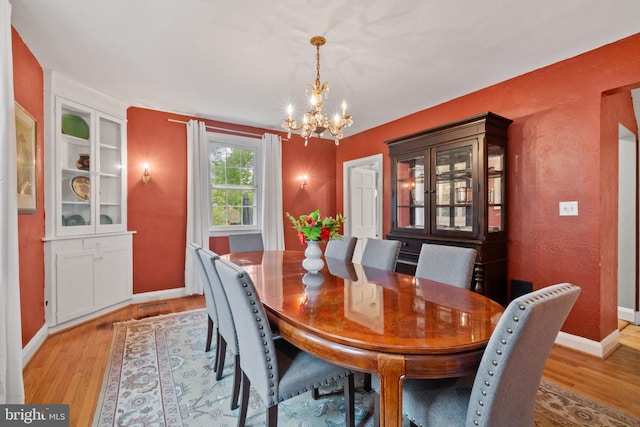 dining space featuring a chandelier, light wood-type flooring, and baseboards
