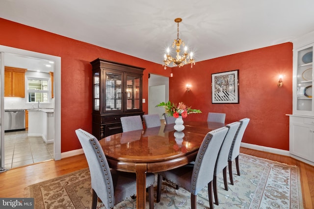 dining room featuring a chandelier, light wood-style floors, and baseboards