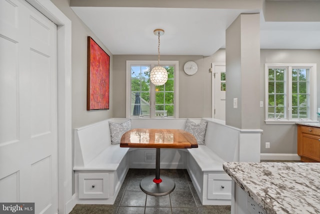 dining room featuring breakfast area, baseboards, and dark tile patterned flooring