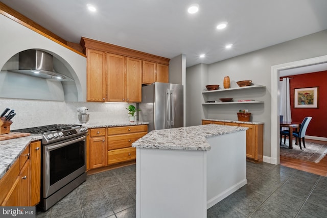 kitchen featuring stainless steel appliances, wall chimney exhaust hood, a kitchen island, open shelves, and dark tile patterned flooring