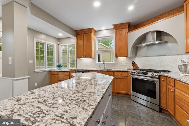 kitchen with appliances with stainless steel finishes, a sink, tasteful backsplash, wall chimney exhaust hood, and recessed lighting