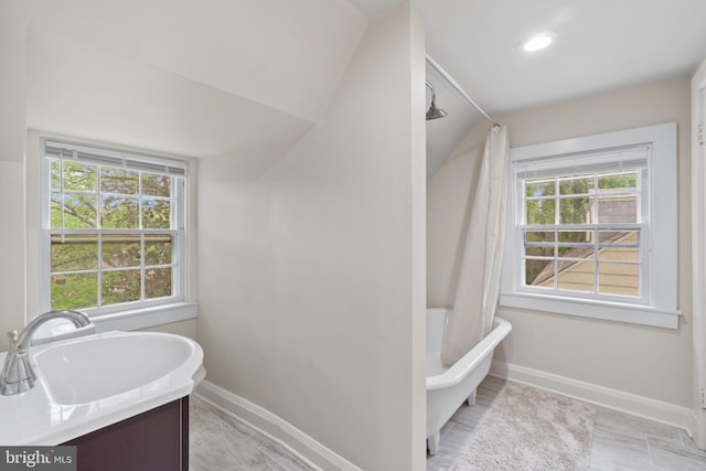 full bathroom with baseboards, plenty of natural light, and a tub