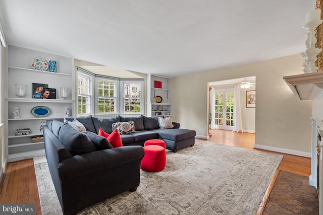 living area with wood finished floors, a fireplace, and built in features