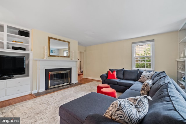 living area featuring wood finished floors, a fireplace with flush hearth, and baseboards