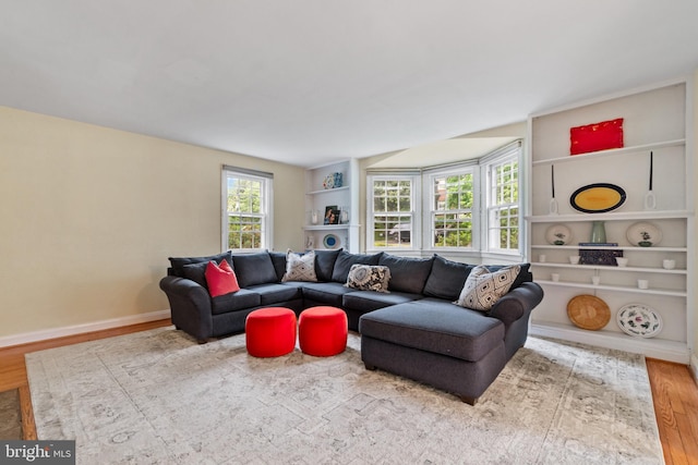 living area with wood finished floors, built in shelves, and baseboards