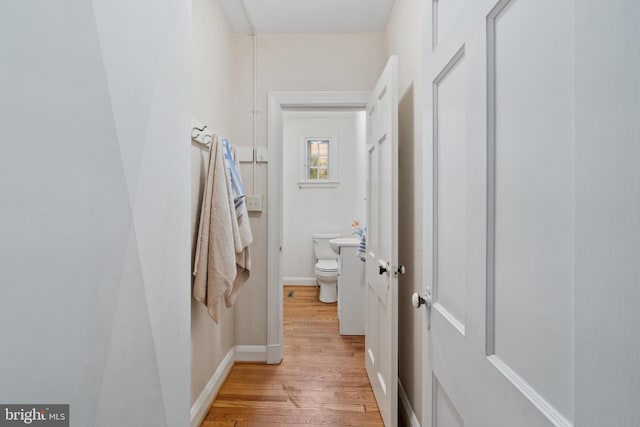 corridor with light wood-type flooring and baseboards