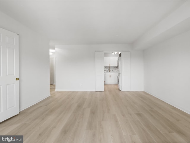 3800 Powell Ln Unit 828, Falls Church, VA 22041 - unfurnished living room with light wood finished floors, washer / clothes dryer, and baseboards