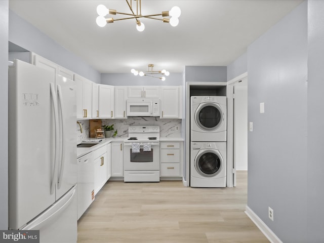 3800 Powell Ln Unit 828, Falls Church, VA 22041 - kitchen featuring white appliances, a chandelier, stacked washer / dryer, a sink, and white cabinetry