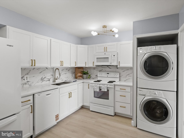 3800 Powell Ln Unit 828, Falls Church, VA 22041 - kitchen featuring white appliances, a sink, estacked washer and dryer, white cabinets, and light countertops