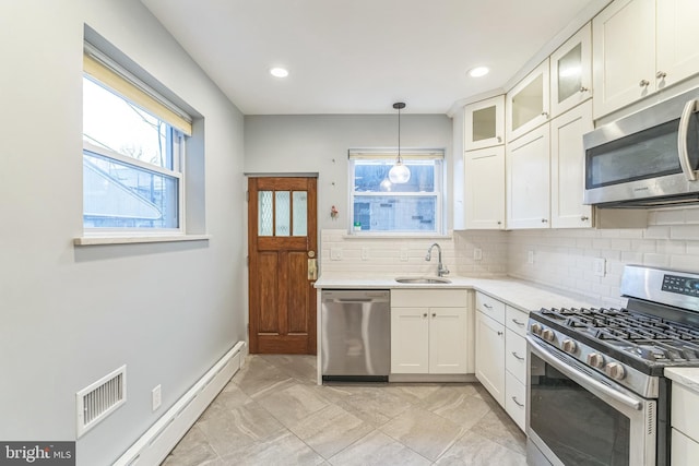kitchen featuring stainless steel appliances, visible vents, a sink, a baseboard heating unit, and tasteful backsplash