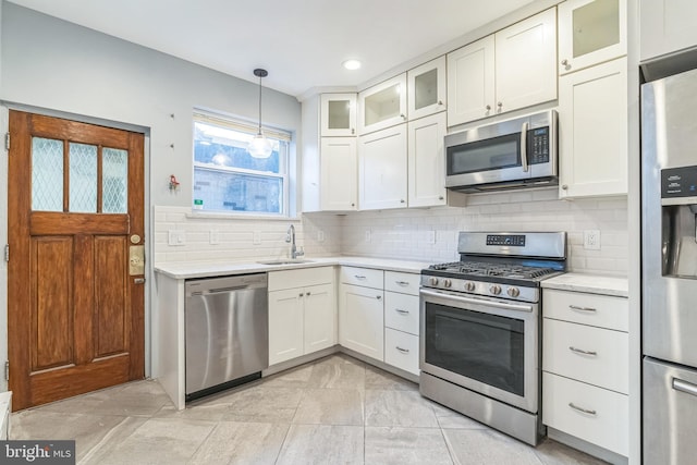 kitchen with a sink, white cabinetry, light countertops, appliances with stainless steel finishes, and hanging light fixtures