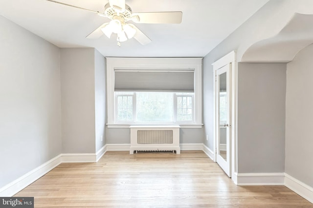 empty room featuring ceiling fan, baseboards, radiator heating unit, and wood finished floors